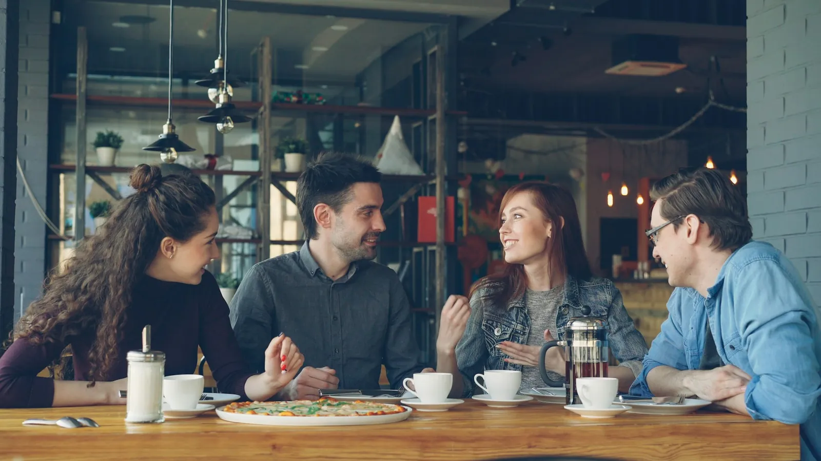 Friends laughing over coffee and pizza in a local café