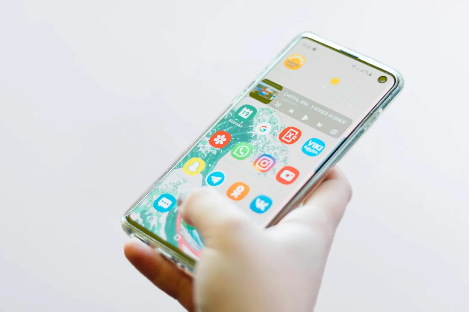 Hand holding an Android smartphone with app icons